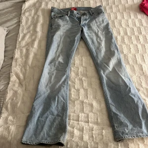 Ljusblå jeans från H&M Divided - Snygga ljusblå jeans från H&M Divided med bootcut-stil. De har en klassisk femficksdesign och knappar i midjan. Perfekta för en avslappnad look.