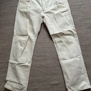 Jens från Woodbird - Säljer ett par (off white färgade) byxor från Woodbird i storlek W36/L32, de är tillverkade i 100% bomull och har en klassisk straight passform. Perfekta för både vår och sommar! Byxorna är i mycket bra skick och har en stilren design med fickor både fram och bak.