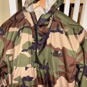 Säljer en snygg camouflage vindjacka från The North Face. Jackan har en dragkedja framtill och en praktisk ficka på magen. Perfekt för höst och vår, med en cool och avslappnad stil. Den är i mycket bra skick och redo för nya äventyr!