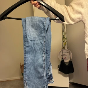 Blå jeans i bra skick - Säljer ett par klassiska blå jeans med slits vid benen i bra skick. De har en normal passform och är perfekta för vardagsbruk. Jeansen har en traditionell femficksdesign och är tillverkade i ett slitstarkt denimtyg. Perfekta för både höst och vår!