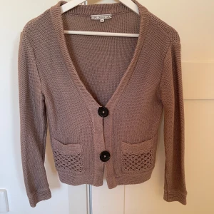 Beige stickad cardigan från DAGMAR - Säljer en superfin beige stickad cardigan från Dagmar i storlek M. Den har två stora knappar framtill och snygga fickdetaljer. Passar både till vardags och lite finare tillfällen. Något liten i storlek och skulle säga att det är mer som en S. Använd fåtalet gånger, utan anmärkningar. 