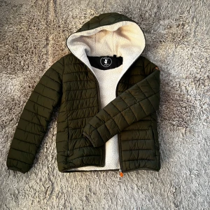 Save The Duck Jacka - Säljer en snygg militärgrön puff/dunjacka från Save The Duck i storlek 14 (XS-S). Jackan är väldigt bekväm och varm, perfekt nu inför vintern. Den är i mycket bra skick, det finns endast en deffekt - ett litet hål vid vänster ficka. Bortsett från det är jackan i princip som ny. Nypris är omkring 1500-2000kr. Bara att skriva ifall du har några frågor! 🤝