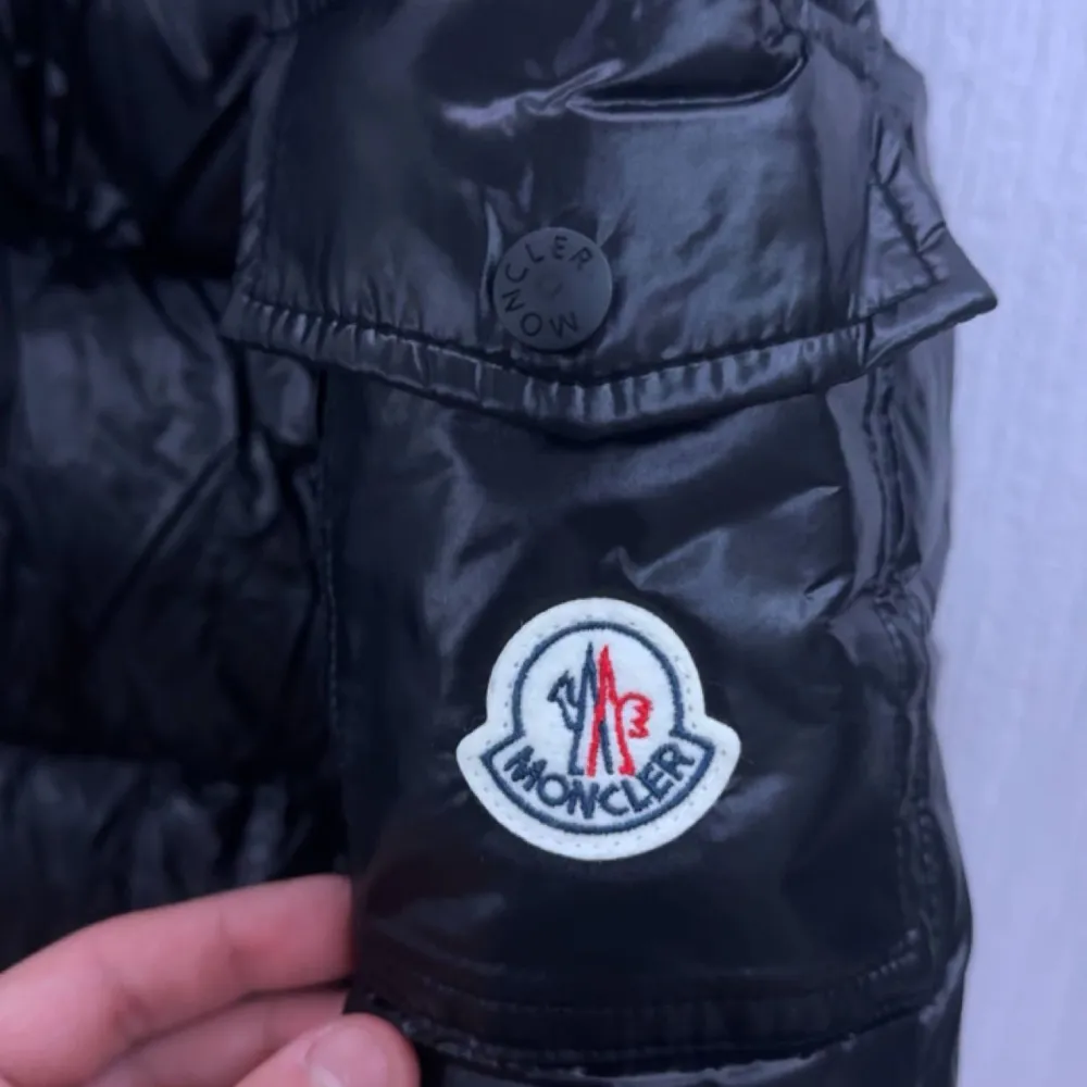 Säljer en snygg svart pufferjacka från Moncler i nytt skick. Jackan är perfekt för vintern med sitt quiltade mönster och långa ärmar. Den har en dragkedja framtill och Monclers logga på ärmen. Supervarm och stilren, perfekt för kalla dagar! 🖤Kommer med alla tags och även den kända moncler triangeln, nfc och qr kod funkar utan problem, storleken är M men kan passa S! helt ny endast testad, pris kan diskuteras!. Jackor.