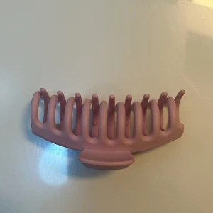 Rosa hårklämma - Snygg och praktisk rosa hårklämma i plast. Perfekt för att snabbt sätta upp håret i en stilren look. Klämman har en enkel design med starkt grepp som håller håret på plats hela dagen. Passar både till vardags och festliga tillfällen.