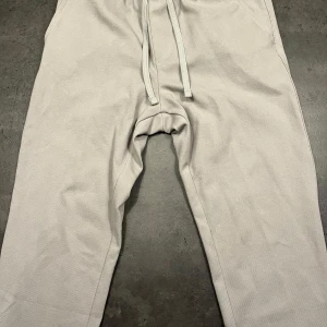 Beige stilig joggerbyxa med snörning - Säljer ett par bekväma beige/grå stiliga joggerbyxor från ZARA i bra skick. De har en avslappnad passform med snörning i midjan för justerbar komfort. Perfekta för en chill dag hemma eller vardaglig tillställning. Passar till alla säsonger och är ett måste i garderoben! Nypris 500:-