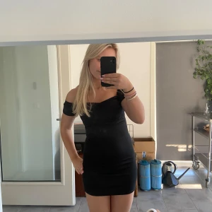 Svart offshoulder klänning - Snygg svart offshoulder klänning i tight passform. Perfekt för fest eller en utekväll. Klänningen är kort och framhäver figuren på ett stilrent sätt. Ett måste i garderoben för alla som älskar klassiska och eleganta plagg.