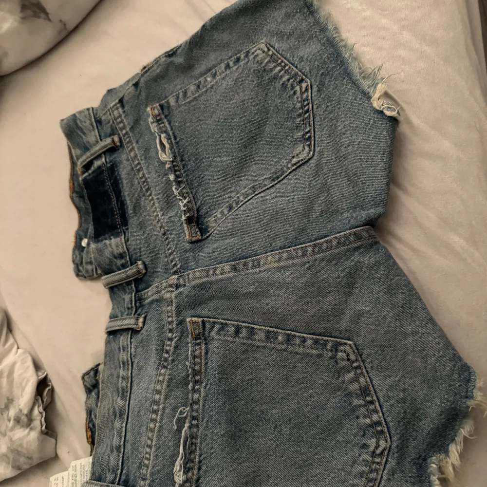 Säljer ett par blå jeansshorts från Zara i storlek S, De har en snygg slitning och fransiga kanter för en avslappnad look. Perfekta för sommardagar eller festivaler! . Shorts.