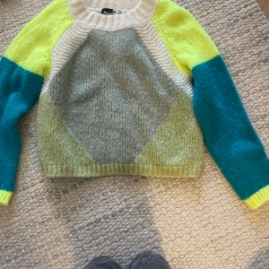 Färgglad stickad tröja från oui  - Säljer en superfin och färgglad stickad tröja från oui. Den har en cool kombination av grått, gult och turkost med långa ärmar. Perfekt för att liva upp höst- och vintergarderoben! Tröjan är i bra skick och väldigt mysig att ha på sig. Passar perfekt till jeans eller kjol. 🌟