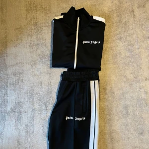 Palm angels  - Hej! Säljer nu en svart tracksuit från Palm Angels med vita detaljer. Riktigt go nu till vintern och funkar till hemma och i skolan. En liten defekt som man ser på bild 4. Storlek L! Kontakta innan vid köp och ställ gärna frågor! MVH Carusfashion 