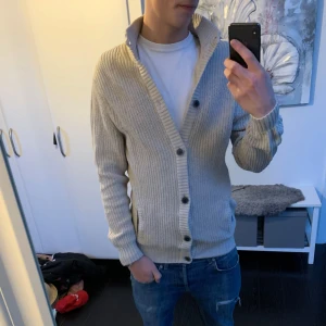 Beige stickad kofta - Säljer en snygg beige stickad kofta med knappar. Perfekt för kyliga dagar, den har en skön passform och ribbade detaljer vid ärmslut och nederkant. Koftan är i bra skick och passar både till vardags och lite finare tillfällen. Ett måste i garderoben för grabbar till  höst och vinter!! Hör gärna av dig vid frågor, pris ej hugget i sten 🪨 