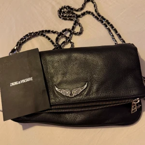 Svart axelväska från Zadig & Voltaire - Snygg svart axelväska i skinn från Zadig & Voltaire med cool kedjerem och dragkedja. Perfekt för både vardag och fest! Kvitto medföljer 🖤
