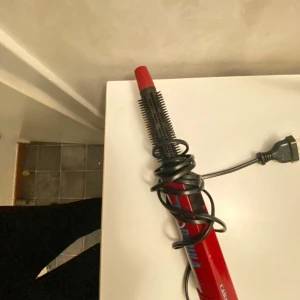 Värmeborste - Röd och svart locktång med sladd, perfekt för att skapa snygga lockar och volym i håret. Den har en smal design och en borste för enkel styling. Perfekt för både vardag och fest!  PRISET KAN DISKUTERAS!