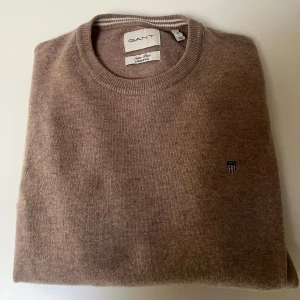 Beige ulltröja från GANT - Säljer en superfin beige tröja från GANT i superfint lammull. Den är i storlek S och har en klassisk rund halsringning. Perfekt för kyliga dagar och ger en stilren look. Tröjan är i mycket bra skick (näst intill ny) och redo för en ny ägare. 🧥✨Ta denna tröjan och den andra på min profil för 1100kr