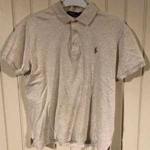 Grå pikétröja från Ralph Lauren - Säljer en klassisk grå pikétröja från Ralph Lauren i storlek M. Tröjan har en slim fit passform och är gjord av mjuk bomull. Den har tre knappar framtill och det ikoniska broderade logotypen på bröstet. Perfekt för både vardag och lite finare tillfällen! Pikén är i ett 9/10 skick och är som ny. Nypris var 1200kr mitt pris 400kr. Om du undrar något så tveka inte på att höra av dig.