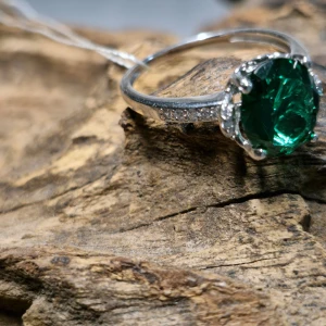 Silverring med grön sten, storlek 18 - Snygg silverring med en stor, glittrande grön sten i mitten. Ringen har små, klara stenar infällda längs sidorna som ger extra bling. Perfekt för att göra ett statement på festen eller som en speciell present. Den gröna stenen är infattad i en elegant klofattning som verkligen framhäver dess skönhet. 
