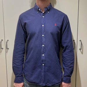 Polo Ralph Lauren Skjorta Marinblå - Skjortan är i mycket bra skick och är i storlek large slim fit men passar medium se måtten.                                          Bredd: 57,5 Längd: 75 Modellen på bilden är 185. Priset går att diskutera! Nypris: 1700kr