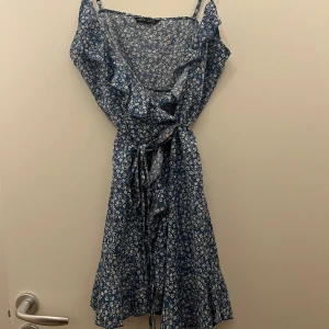 Blå klänning  - Fin blå klänning från SHEIN. Sitter superfint på men har tyvärr blivit för stor för mig. Omlottklänning som man knyter runt och justerbara band över axlarna. Storlek M men passar nog även S. 