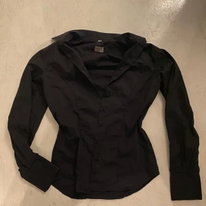 Skjorta - Svart skjorta som sitter åt runt lite runt midjan!! Super fin. Lite solblekt 