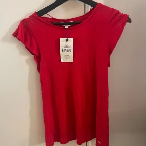 Röd topp från Hampton Republic - Säljer en röd tshirt från Hampton Republic. Helt oanvänd tom prislapp kvar. Den har även fina volangdetaljer på ärmarna