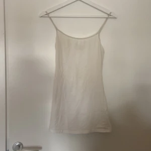 Vit linnetopp från Divided - Säljer en enkel och stilren vit linnetopp från Divided. Den är ärmlös med smala axelband och har en skön passform. Perfekt för sommardagar eller som ett basplagg i garderoben.