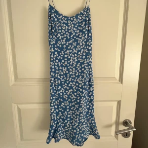 Blå blommig klänning - En supersöt blå miniklänning med vita blommor på från zara. Helt oanvänd med prislappkvar. Storlek S. Skriv gärna för fler bilder.
