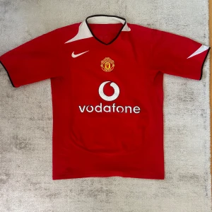 Manchester United 2004-2006, Storlek S - Manchester United hemmatröja från 2004-2006 Vodafone sponsor   Storlek: S  Finns slitage på trycket men övrigt bra skick! 