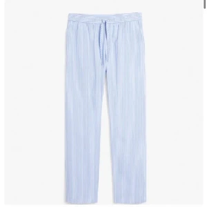 Blå- och vitrandiga byxor - Säljer ett par superbekväma blå- och vitrandiga byxor. De har en avslappnad passform med resår i midjan och snörning för extra komfort. Perfekta för en chill dag hemma eller en avslappnad promenad. Materialet känns lätt och luftigt, vilket gör dem idealiska för varmare dagar.