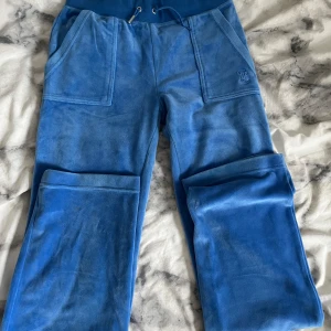 Juice byxor  - Ett par blåa juicy byxor i bra skick! Metalldelen på ena snöret är borta annars är byxorna i mycket bra skick! Byxorna har knappar där bak utan repor eller andra skador. 