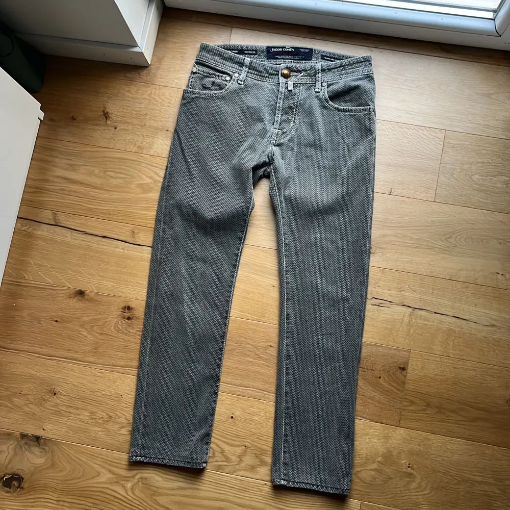 Säljer ett par snygga grå jeans från Jacob Cohen. De har en unik mönstrad design och är i ett klassiskt snitt. Jeansen har en knappgylf och fem fickor, vilket ger dem en tidlös look. Perfekta för både vardag och fest! Mvh ItsForFits 🌟. Jeans & Byxor.