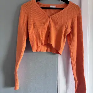 Säljer en superfin orange ribbad kofta från Glamorous Care. Den är croppad och har en v-ringad design med knappar framtill. Perfekt för höst och vår när du vill ha något lätt men ändå snyggt. Passar perfekt till både jeans och kjol!