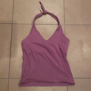 Lila halterneck-linnetopp - Lila halterneck-linnetopp med knytning i nacken. Toppen har en v-ringad design har dubbelt tyg över bröstet 