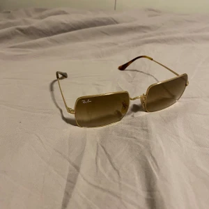Ray Ban Rectangle 1969 - Tja! Säljer nu dessa snygga Ray Bans då de inte har kommit till användning särskilt mycket. De är använda vid ett fåtal tillfällen och är därmed i mycket gott skick. Inga repor på varken glas eller båge. Hör av dig vid minsta fundering! Nypris: 2110 kr på Ray-Bans hemsida.