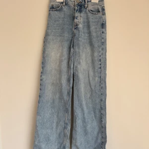 Ljusblå jeans med hög midja - Snygga ljusblå jeans med hög midja och en avslappnad, rak passform. Perfekta för en casual look. Klassisk femficksdesign med knapp och dragkedja framtill. Se vissa defekter på bilderna som går bort i tvätten