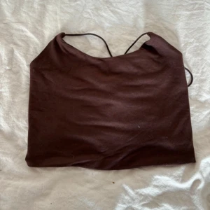 Brunt linne med snörning i ryggen - Brunt linne med snörning i ryggen. Perfekt för en trendig look.