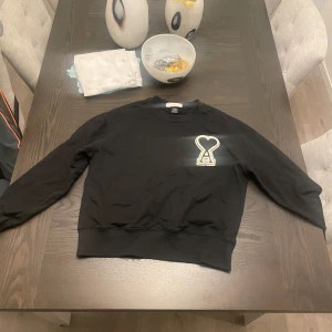 Ami Paris tröja  - Säljer en stilren svart tröja från Ami paris tröja med ett unikt hjärtmönster på bröstet. Tröjan har långa ärmar och ribbade muddar vid ärmslut och nederkant. Perfekt för en casual look. Knappast använd med !! Vid snabb affär kan jag gå ner i pris 