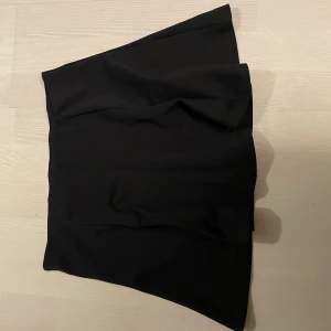 Svart kjol från Gina Tricot - Snygg svart kjol från Gina Tricot i en stilren design. Perfekt för att matcha med olika toppar och accessoarer. Kjolen har en asymmetrisk form som ger en modern touch.