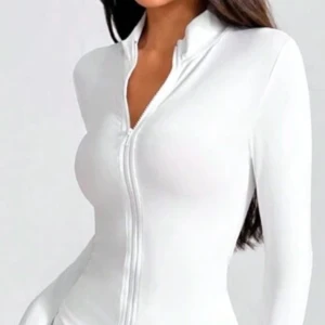 Vit långärmad tröja med dragkedja - Snygg och stilren vit långärmad tröja med dragkedja framtill. Perfekt för en casual look eller att klä upp med accessoarer. Tröjan har en tight passform som framhäver figuren. 