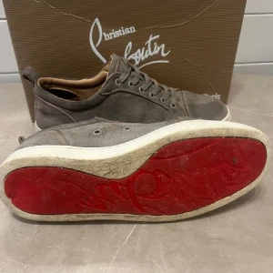 Grå sneakers från Christian Louboutin - Snygga grå sneakers från Christian Louboutin med den ikoniska röda sulan.