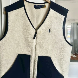 Ralph Lauren väst - Vit och mörkblå väst från Ralph Lauren i storlek S (man). Köpt för 2495 kr, använd mycket med några små fläckar men inget som syns. 