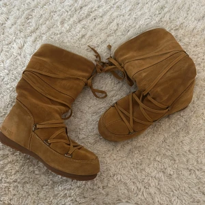 Moon Boots - Säljer ett par bruna Moon Boots i mocka med snörning. De har en robust sula och är perfekta för kalla dagar. Insidan är fodrad för extra värme och komfort.