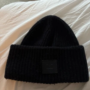 Svart ribbad mössa från Acne Studios - Snygg svart ribbad mössa från Acne studios. Lite nopprig men utöver inga andra defekter. 