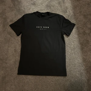 Svart t-shirt från Dope Snow - Snygg svart t-shirt från Dope Snow med tryck på både fram- och baksida. Framsidan har texten 'DOPE SHOW' och baksidan har ett coolt bergsmotiv i rosa och blått med texten 'DOPE SNOW MMIX'. Perfekt för en avslappnad stil.