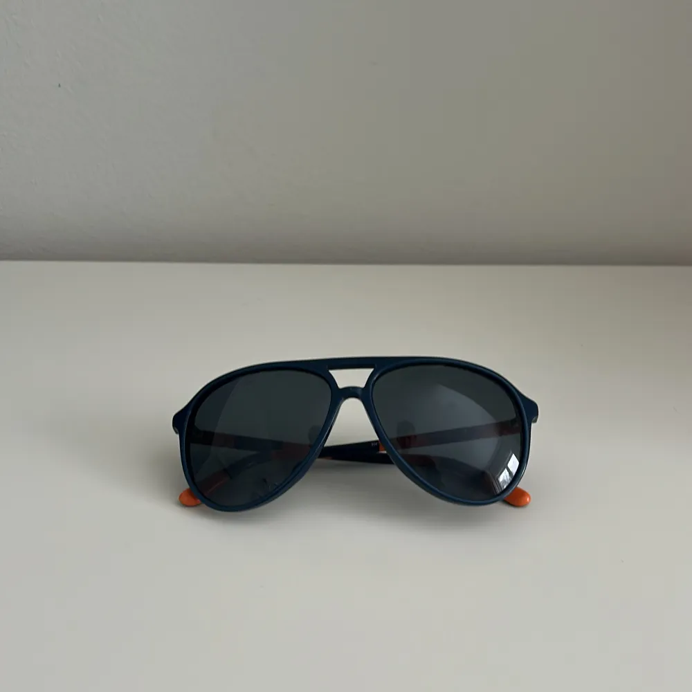 Snygga mörkblå solglasögon från Ralph Lauren med orange detaljer. Modellen är klassisk och passar perfekt för soliga dagar. Kommer med ett praktiskt fodral för säker förvaring. Är villig och gå ner i pris! 😁. Asusteet.