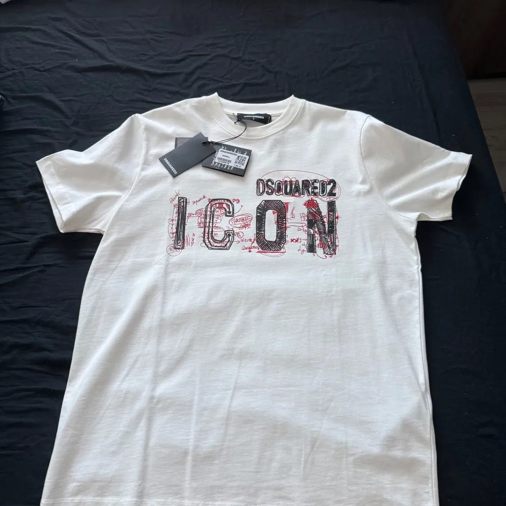 Snygg vit t-shirt från Dsquared2 med trycket 'ICON' i svart och rött på framsidan. Perfekt för en stilren och modern look. Helt ny med tags. Öppen för byten. Pris kan diskuteras. För mer bilder eller några frågor så är de bara att skriva. Kan mötas upp i Jönköping.. T-paidat.