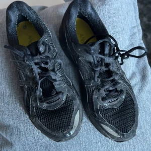 Svarta Asics löparskor - Säljer ett par svarta Asics löparskor med snörning och gel-dämpning. Skorna har en slitstark sula och är perfekta för löpning och träning. Skorna har inte inlägg för den jag säker billigt.
