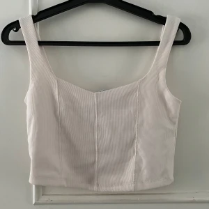 Beige ribbad linnetopp från Stradivarius - Säljer en stilren beige ribbad linnetopp från Stradivarius. Toppen har breda axelband och en enkel design som passar perfekt till sommaren. Perfekt för en avslappnad look eller att klä upp med accessoarer.