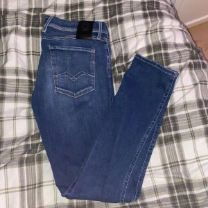 Blå jeans från Replay - Snygga blå jeans från Replay i modellen Anbass. De har en klassisk femficksdesign med dragkedja och knapp. Perfekta för en avslappnad stil. Priset kan självklart diskuteras och kan vara intresserad av byten!