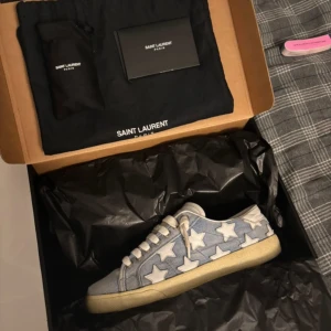 Saint Laurent - Snygga blå sneakers från Saint Laurent med vita stjärnor och snörning. Skorna har en retro look med en beige sula och är perfekta för en avslappnad stil. Nypris ligger på 7000 så mitt pris är väldigt bra. Skorna tillverkas inte längre!! Pris kan Diskuteras 