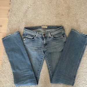 Blå jeans med bootcut - Snygga blå jeans med bootcut-stil och klassisk femficksdesign. De har en lätt slitning för en avslappnad look och stängs med dragkedja och knapp. Perfekta för en casual outfit.