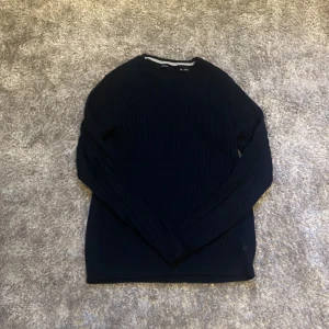 Mörkblå stickad tröja från Jack & Jones - Säljer en stilren mörkblå stickad tröja från Jack & Jones. Tröjan har en rund halsringning och är perfekt för kyligare dagar. Passar bra till både jeans och chinos.